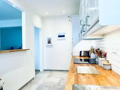 a kitchen with white walls and a wooden counter top at Magnifique appartement spacieux in Brussels