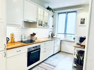 a white kitchen with white cabinets and a window at Magnifique appartement spacieux in Brussels