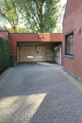 a brick parking lot with two garage buildings at Maison Spacieuse near Brussels in Meise