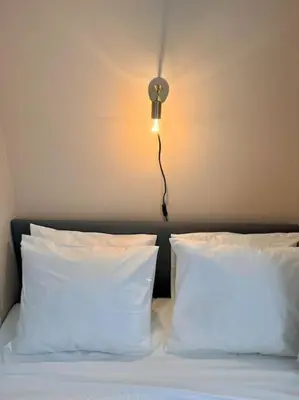a bed with two pillows and a light on the wall at Chez Louise - A haven of peace in Brussels in Brussels