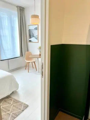 a bedroom with a green and white wall and a table at Chez Louise - A haven of peace in Brussels in Brussels