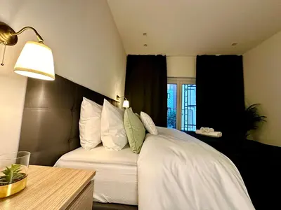 a bedroom with a bed with white sheets and green pillows at Luxury Suites Park by Rikas Hotels in Antwerp