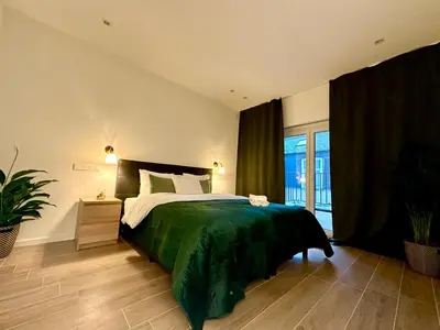 a bedroom with a large bed with a green blanket at Luxury Suites Park by Rikas Hotels in Antwerp