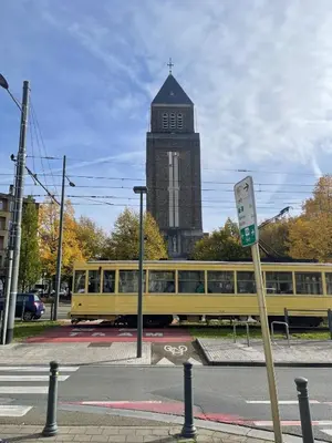 a yellow train on a street with a clock tower at La belle étoile de Bruxelles in Brussels
