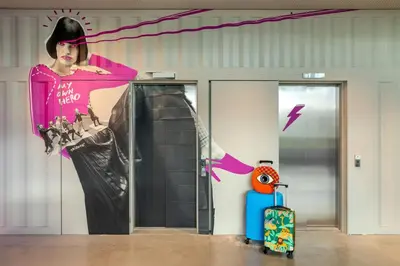 a wall with a painting of a woman and a suitcase at Moxy Antwerp in Antwerp