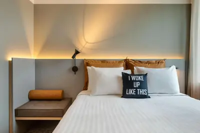 a bedroom with a bed with two pillows and a bench at Moxy Antwerp in Antwerp