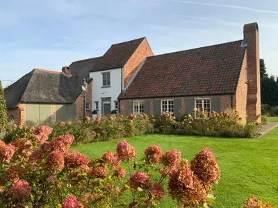 a house with a green yard with flowers at B&B de Graaf van Poppel in Poppel