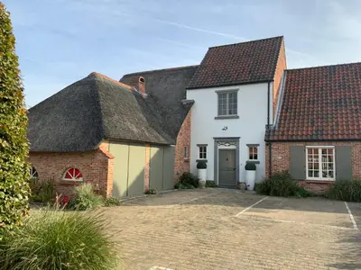 a white house with a thatched roof at B&B de Graaf van Poppel in Poppel