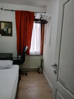 a room with a bed and a desk and a window at Kamertje in Asse