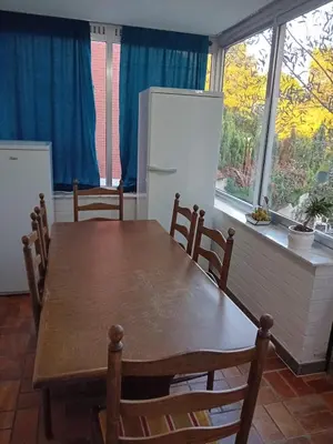a kitchen with a wooden table and a refrigerator at Kamertje in Asse