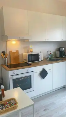 a kitchen with white cabinets and a microwave and a table at Apartment near atomium with parking in Vilvoorde