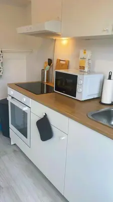 a white kitchen with a microwave and a sink at Apartment near atomium with parking in Vilvoorde