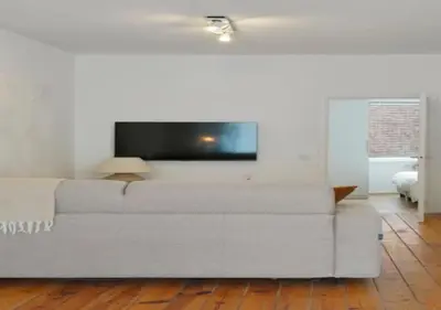 a white couch in a living room with a flat screen tv at Top Location - City Center 1BR with Stylish Decor in Antwerp