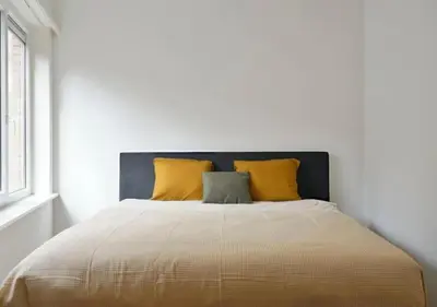 a bed with yellow pillows in a white bedroom at Hip & Historic Stay Antwerp in Antwerp