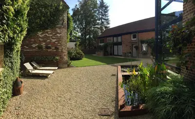 a garden with a bench and a brick building at B&B Den Engel in Kortenberg
