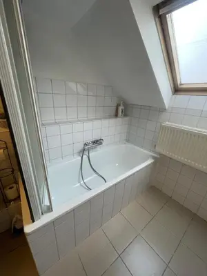 a white bath tub in a bathroom with a window at Attic European Quarter in Brussels