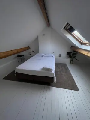 a white bedroom with a bed in a attic at Attic European Quarter in Brussels