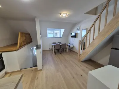 a living room with a dining room table and stairs at Cosy duplex in center of Brussels in Brussels