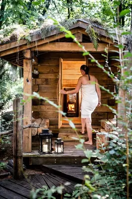 a woman in a white dress standing outside of a wooden building at Tjiftjaf in Retie