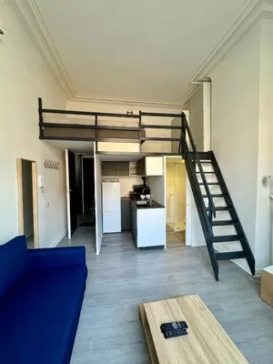 a living room with a blue couch and a loft bed at Studio avec chambre en mezzanine in Brussels