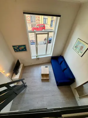 a living room with a blue couch and a window at Studio avec chambre en mezzanine in Brussels
