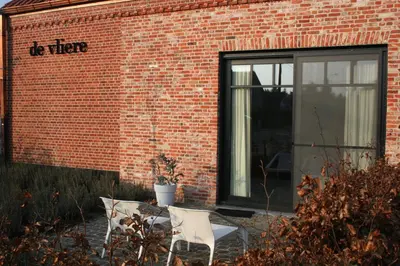 two white chairs sitting in front of a brick building at Guesthouse De Vliere in Beerse