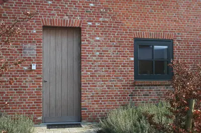 a brick building with a wooden door and a window at Guesthouse De Vliere in Beerse