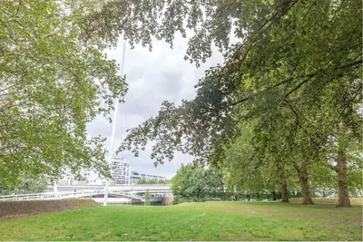 a park with trees and a bridge in the background at Lightful architectural house in Ghent