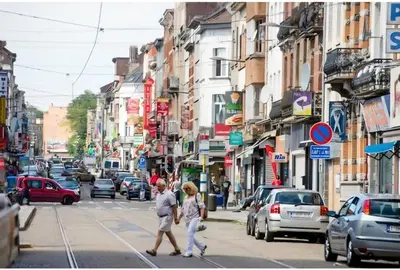 two people crossing a busy city street with cars at Appartement Bruxelles Belgique in Brussels