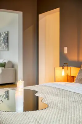 a bedroom with a bed and a candle on a table at Spacious & Luminous Gem in Historic Ghent Building in Ghent