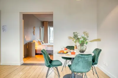 a dining room with a table and green chairs at Spacious & Luminous Gem in Historic Ghent Building in Ghent