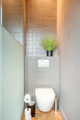 a bathroom with a toilet with a plant on top at Spacious & Luminous Gem in Historic Ghent Building in Ghent