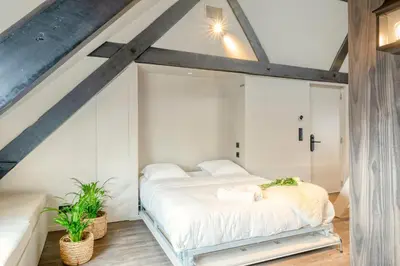 a bedroom with a white bed in a attic at Charming Attic Retreat in Historic Ghent Center in Ghent