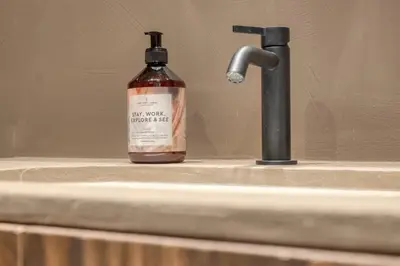 a bottle of alcohol sitting on a sink next to a faucet at Charming Attic Retreat in Historic Ghent Center in Ghent