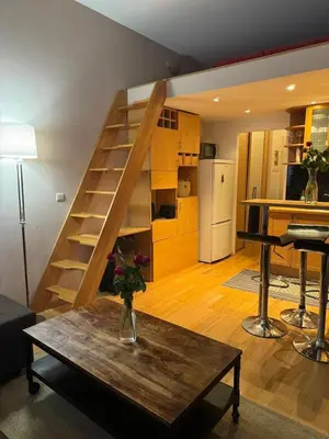 a living room with a staircase and a table with a vase at B&B appartement in Brussels