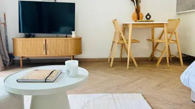 a living room with a tv and a white table at MY Cabane -POOL HOUSE avec Sauna privée près de Bruxelles in Oppem