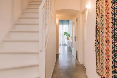 a hallway with white walls and stairs with a rug at Logieslogees in Tielrode