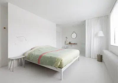 a white bedroom with a bed and a table at Logieslogees in Tielrode