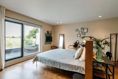 a bedroom with a bed and a large window at Logieslogees in Tielrode