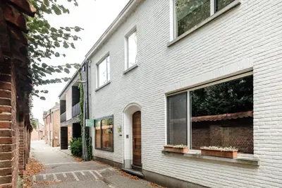 a white brick building with windows on a street at Logieslogees in Tielrode