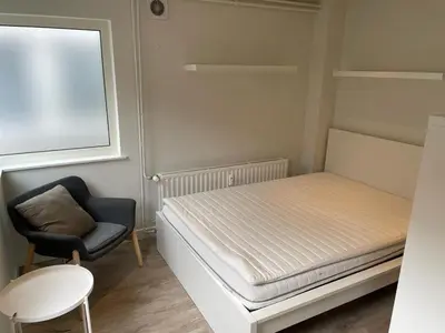a small bedroom with a bed and a chair at voskenslaan WS in Ghent
