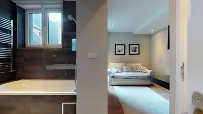 a bathroom with a tub and a couch in a room at Villa Sablon in Brussels