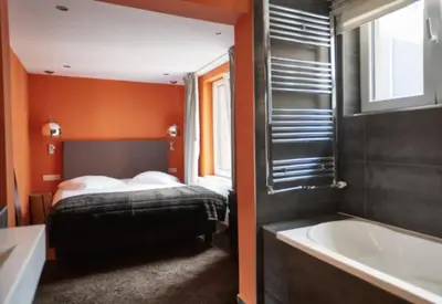 a bedroom with a bed and a bath tub next to a bath tub at Villa Sablon in Brussels