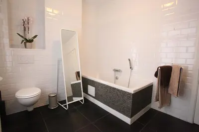 a white bathroom with a tub and a toilet at B&B Sablon Antwerp in Antwerp