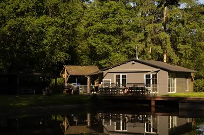 a small house next to a body of water at Unieke chalet aan het water in Lille