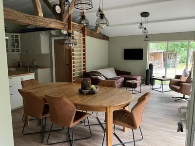 a kitchen and living room with a wooden table and chairs at Unieke chalet aan het water in Lille