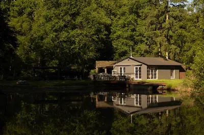 a house sitting on the side of a lake at Unieke chalet aan het water in Lille