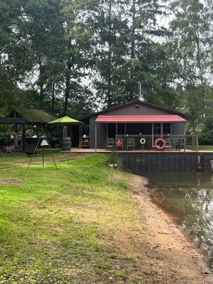 a building with a red roof next to a body of water at Unieke chalet aan het water in Lille