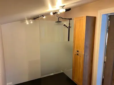 a bathroom with a shower and a glass wall at Unieke chalet aan het water in Lille