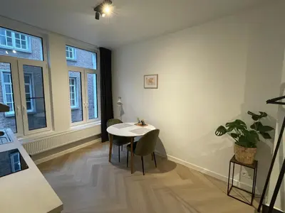 a dining room with a table and chairs and windows at Stadsstudio op toplocatie in Antwerp